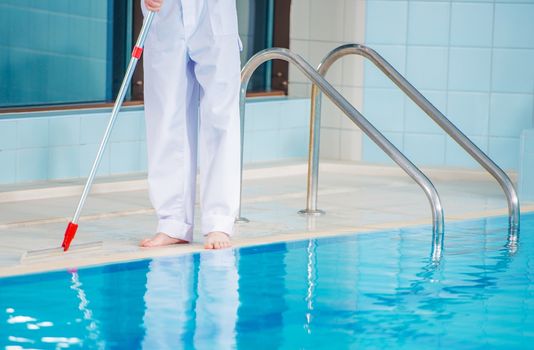 Interior Swimming Pool Cleaning. Caucasian Worker Cleaning Ceramic Sides of the Pool. 