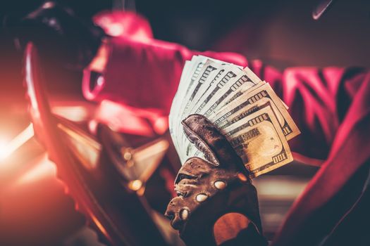 Casino Jackpot Winner with Pile of One Hundred Dollars Banknotes While Seating Inside His Classic American Car. Closeup Photo. Las Vegas Gambling Theme.