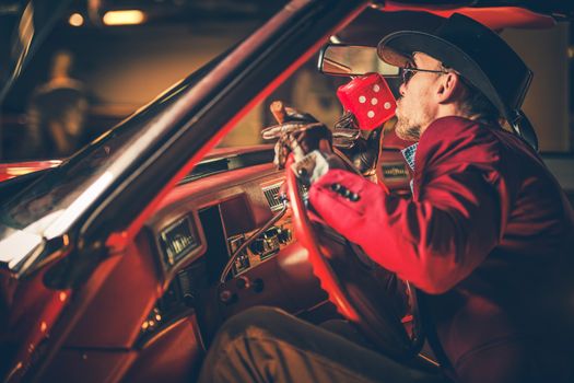 Lucky Casino Winner Kissing Red Craps Dices Inside His Classic Car. Caucasian Men in His 30s Wearing Burgundy Suite and Cowboy Hat.