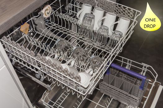 View from above on an open dishwasher with clean cup, glasses and plates.
