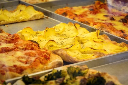 close-up view of a rectangular pizza slice stuffed with potatoes, tomato and cheese