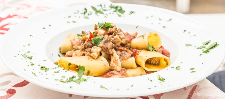 Otranto town, Puglia Region, South of Italy. Traditional Paccheri pasta with Swordfish, served with tomato, parsley, olive oil. Daylight, real restaurant in Otranto.