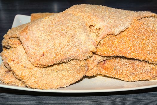 Freshly baked raw escalope
 of veal on a white plate.