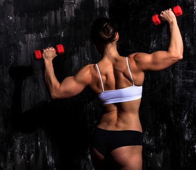 Fitness woman with red dumbbells on a dark background