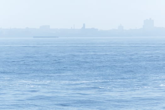 Misty sea on blue sky and city skyline in background