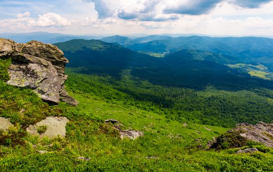 rocky cliff over the grassy valley. beautiful summer landscape with mountain ridge in the distance