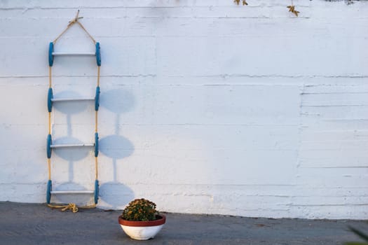 Conceptional geometrical composition of blue marine ladder leaning against vertical white painted wall