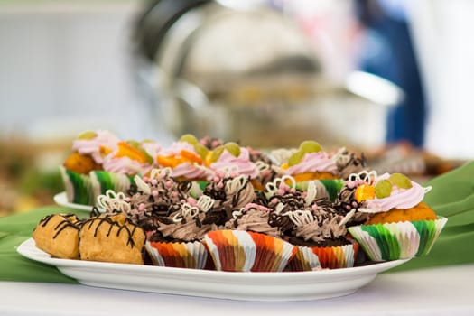 Cupcakes colored wrappers on a plate standing on the table.