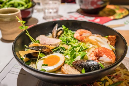 A large bowl of Japanese Ramen with egg, meat, prawn, mussel and vegetable