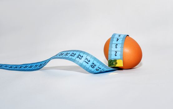 Egg wrapped in blue measuring tape, slimming concept.