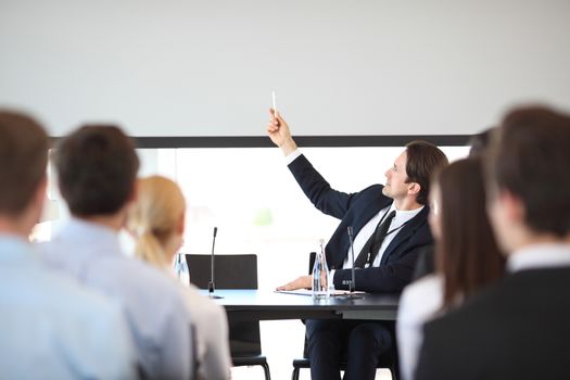 Speakers at business meeting at the table with microphones pointing at blank whiteboard with copy space