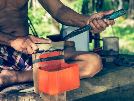 Gardener sharpen rubber tapper knife by grind stone, Thailand