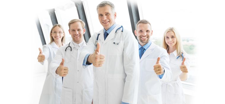 Medical team of doctors and in hospital showing thumbs up