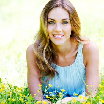 beautiful young woman in blue dress lying on grass