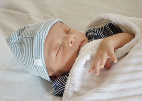 Eurasian newborn baby sleeping on white sheet