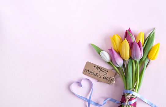 Heart shape ribbon attached to a bunch of flowers with mothers day label