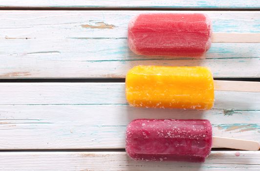 Assorted flavored ice lollies over a wooden background