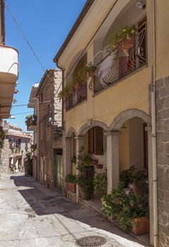 small street in Orgonsolo Sardinia with plants and flowers in the street and windows with shutters and balconies,orgonsolo is famous because of the murales, the wall paintings