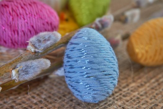 Colorful easter eggs and willow branch on natural jute fabric background. The concept of a happy Easter