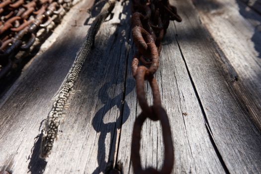 Shade on the old & weathered wood surface, old rust chains