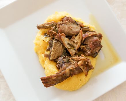 Typical italian food,polenta with Capretto( small goat meat) roasted, view from above.