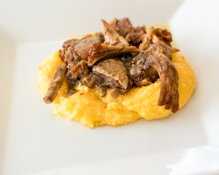 Typical italian food,polenta with Capretto( small goat meat) roasted, close up.