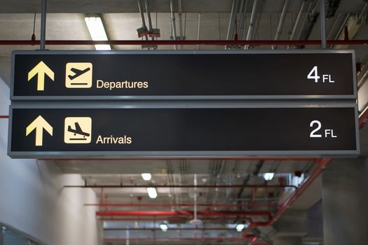 Departure and arrivals information board sign with yellow and white character on black background at international airport terminal.