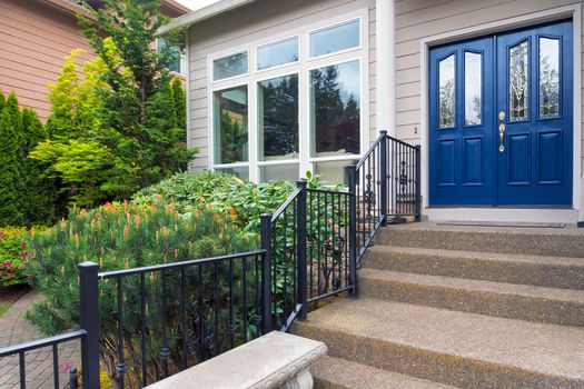 House with blue double doors concrete steps entry by landscaped front yard garden