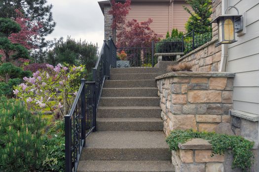 Concrete stair steps with railings and stone wall planters by frontyard garden to house door entrance