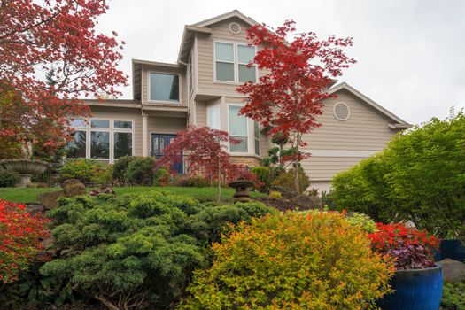 Lush front yard garden landscaping of single family home withwater fountain ceramic pots trees shrubs green grass lawn