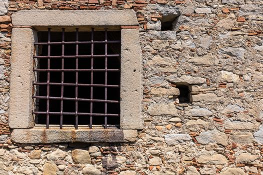 The window with iron gratings on stone wall, for background