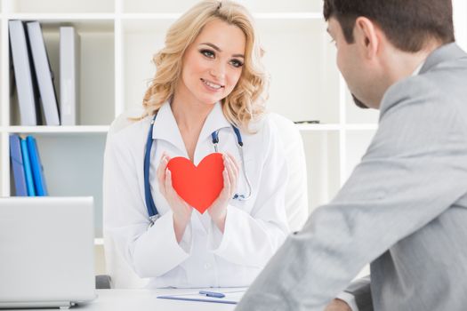 Doctor showing red paper heart to patient, cardio therapeutist consultation