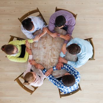 Startup diversity teamwork brainstorming meeting concept, people sitting around the table and holding hands, unity, togetherness