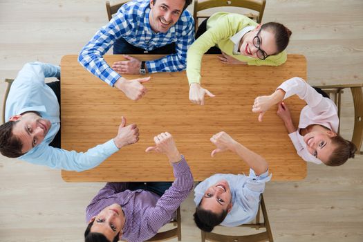 Coworkers with thumbs up sitting at the office table, top view
