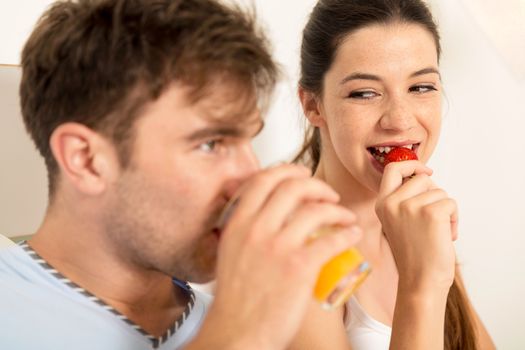 Young couple eating breakfast on bed