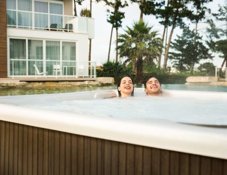 Young couple in a luxury hotel inside a jacuzzi in a rainy day 
