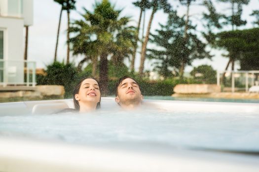 Young couple in a luxury hotel inside a jacuzzi in a rainy day 