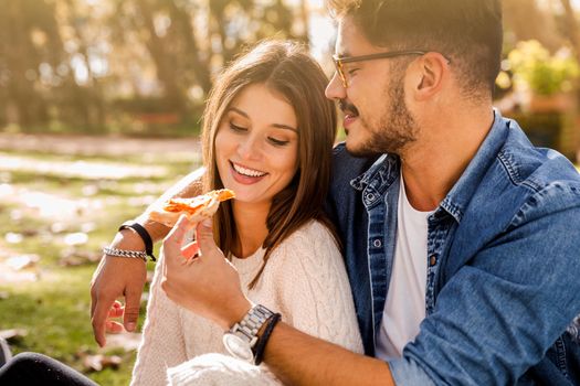 Couple at the park eating pizza