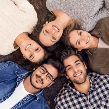 Top view of a group of friends lying on floor and looking at camera