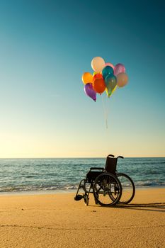 Wellchair on a beach with colored  ballons 