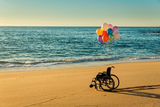 Wellchair on a beach with colored  ballons 