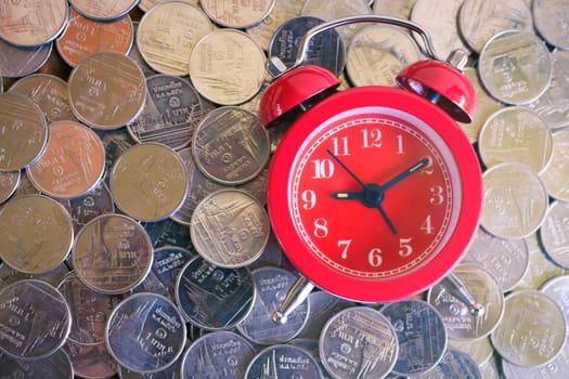 Stack of coins with red fashioned alarm clock for display planning money financial and business accounting concept, time is money concept with clock and coins, time to work at make money, vintage color tone