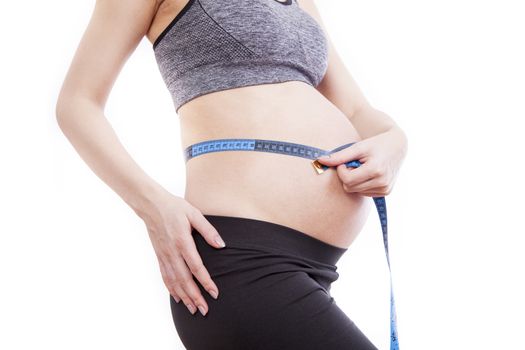 Pregnant woman measures her belly with a measure.