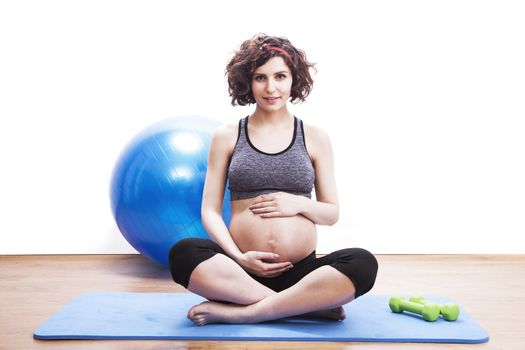 young pregnant woman exercises on the mat. Isolated shot