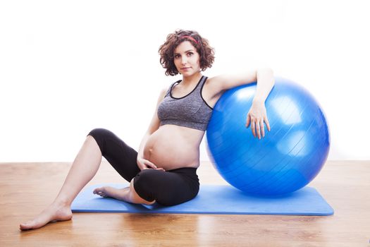 Young pregnant woman exercises with the ball.