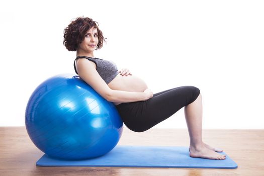 Young pregnant woman exercises with the ball.