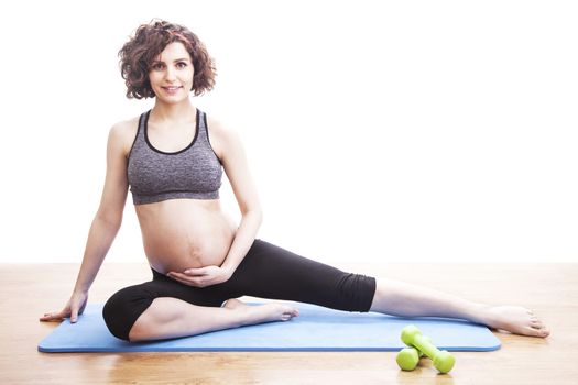 young pregnant woman exercises on the mat. Isolated shot