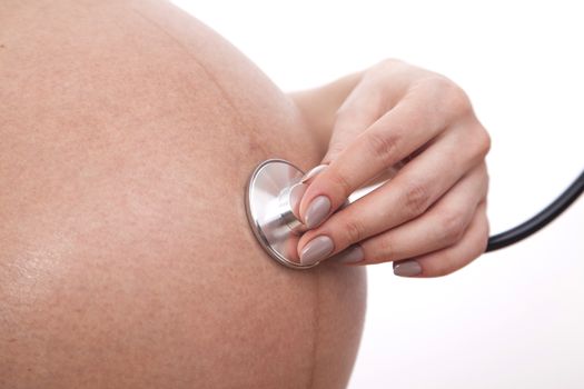 Pregnant woman listens to her child through a stethoscope.