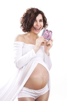 pregnant woman in a white dress holding a tiny baby shoes.