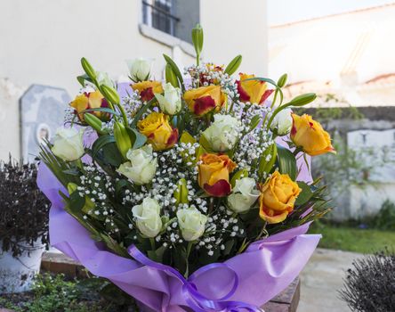 bouquet of flowers as roses and mlily in purple wrap 